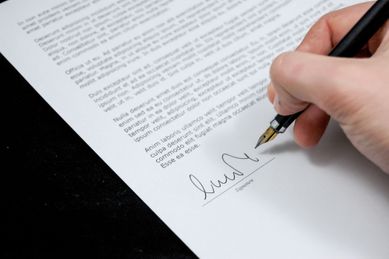 En person som skriver under på et dokument med en font penn